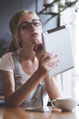 Onun yeni tablet inceleyerek. Çekici gülümseyen kadın pencerenin yakınındaki restoranda otururken dijital tablet kullanma