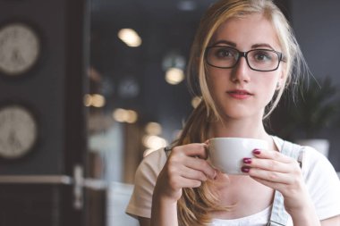 Kahve gün tamamlar. Bir kafede bir kapuçino çekici bir genç kadının portresi