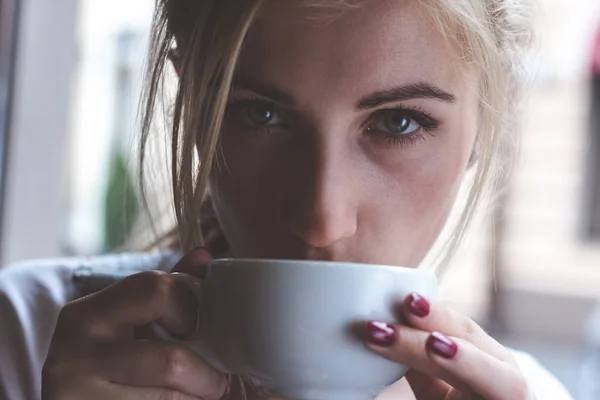 Coffee warms the heart and soothes the soul. Closeup shot of an attractive youmg woman looking at camera with a cup of coffee.