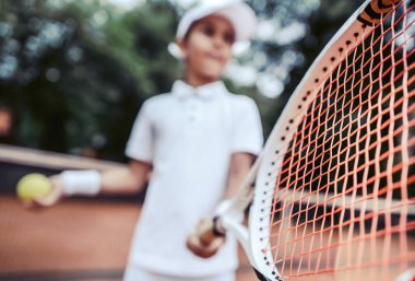 Sportif küçük kız tenis topu hizmet vermeye hazırlanıyor. Tenis top ve raket tutan güzel yong kız görünümünü kapatın. Çocuk tenis oyuncusu hizmet vermeye hazırlanıyor. seçici odak.