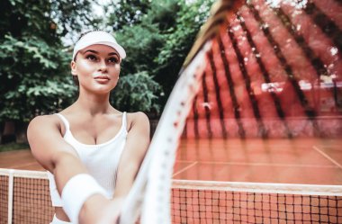 Bir raket tenis kortunda hizmet vermeye hazır tutmak tenisçi. Genç kadın play tenis yaz gün tenis kulübü