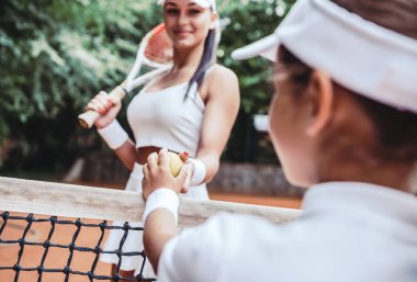 Eğitim tenis birlikte. Çalan kız görüntüsünü ve tenis kortunda pratik koçu kırpılmış. Tenis eğitmen bir top kız çocuğu için servis için verir. Genç çocuk için eğitim.