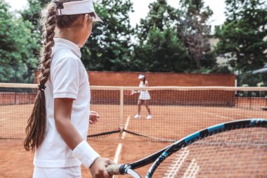 Oynamak hazır. Yan görünümü güzel tenisçi üzerinde arka plan bulanık ile sportif çocuk üzerinde duruldu kırpılmış. Genç kadın tenis kortunda kız çocuktan hizmet vurmaya hazırlanıyor. Aktif egzersiz.
