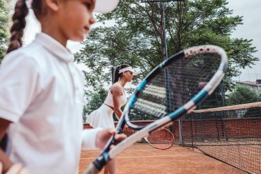 Eğitmen ya da çocuk bir sahada tenis oynamayı öğreterek koç. Yan görünüm.