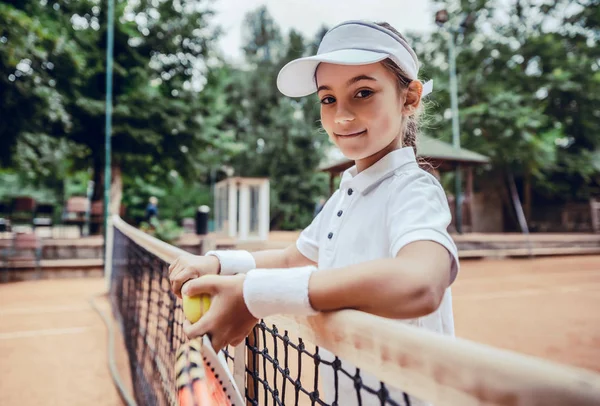 子供は屋外コートでテニスをする スポーツクラブでテニスラケットとボールを持つ女の子 子供のための積極的な運動 子供のための夏の活動 若い子供のための訓練 子供の遊び方 — ストック写真