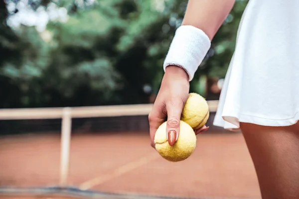 Are you ready to play? Cropped closeup image of a young woman holding tennis balls on court.Healthy lifestyle in tennis club.