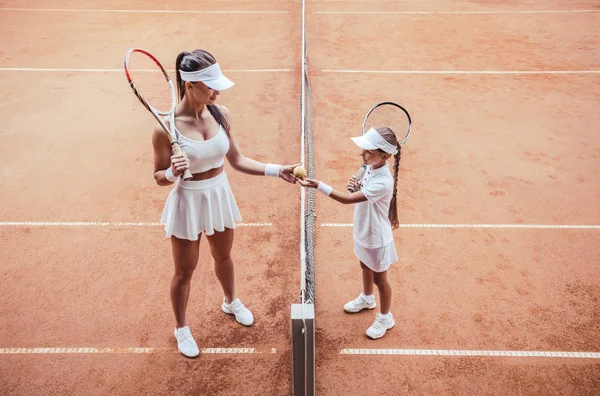 自信を持ってテニスのコーチと試合前にお互いに立っている少女 テニス トレーニングで若い女の子とテニス指導者の平面図です 学習を再生します — ストック写真