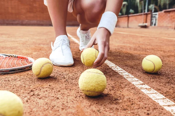 テニスコートで白いスカートを着た若い女性の脚 美しい女性のテニス選手は テニス ボールを地面をピックアップします スポーツ ファッション — ストック写真