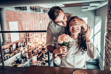 Senin için sürpriz! Güzel romantik çift kafede. Genç adam karısına çiçek sunuluyor.