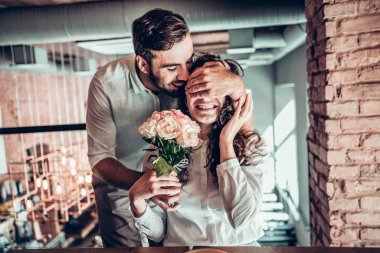 Senin için sürpriz! Güzel romantik çift kafede. Genç adam karısına çiçek sunuluyor.