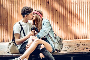 Genç çift öpüşme sahnesinde açık havada otururken. İçme soda ve zevk yaşam.