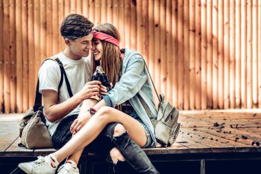 Genç çift sahnede açık havada otururken gülüyor. İçme soda ve zevk yaşam.