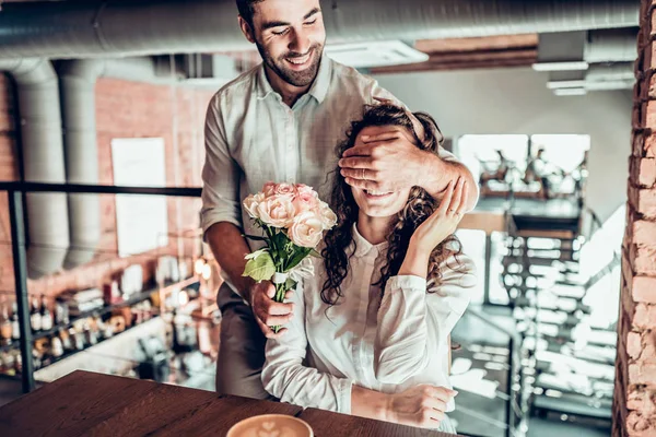 True feelings. Beautiful romantic couple in cafe. Man is presenting flowers to his wife.