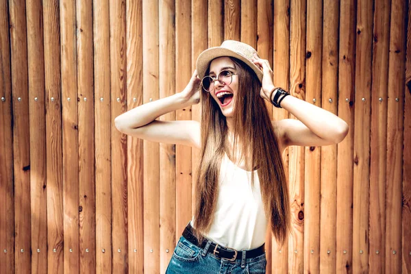 Stylish young woman in sunglasses smiling against wooden background. Beautiful female model with copy space.
