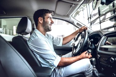 Genç iş adamı sürücü yeni araba sınayın. Yan görünüm