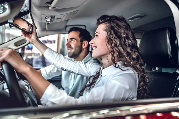 Молодая Пара Выбирает Машину Автосалоне Женщина Смотрит Зеркало Заднего Вида — стоковое фото