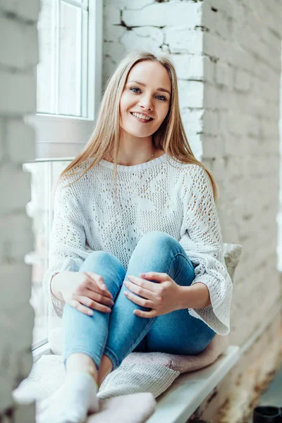 Portret van mooie vrouw zitten op de vensterbank en glimlachen. — Stockfoto