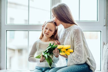 Onlar birbirlerini hazine. Sevgi dolu bir anne ve kızı evde pencere pervazına üzerinde oturan.