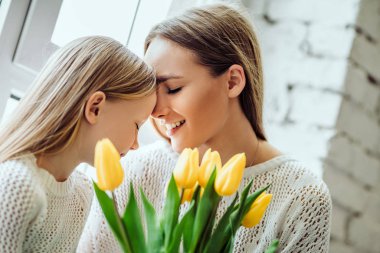 Çok seviyorum. Güzel anne ve genç kızı evde pencere kenarında oturan.