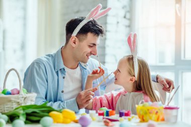 Mutlu Paskalyalar! Baba ve kızı birlikte küçük Paskalya tatili için hazırlarken iyi eğlenceler. Bir sepet Paskalya yumurta, çiçek ve boya tablodur.