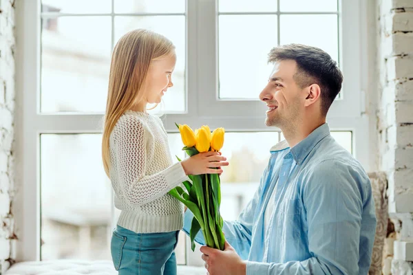 These flowers are for you. Dad gives her daughter a bouquet of tulips. — Stock Photo, Image