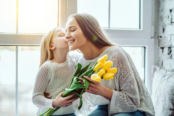 Barnet gratulerer mor og gir tulipaner en blomsterbukett. . – stockfoto