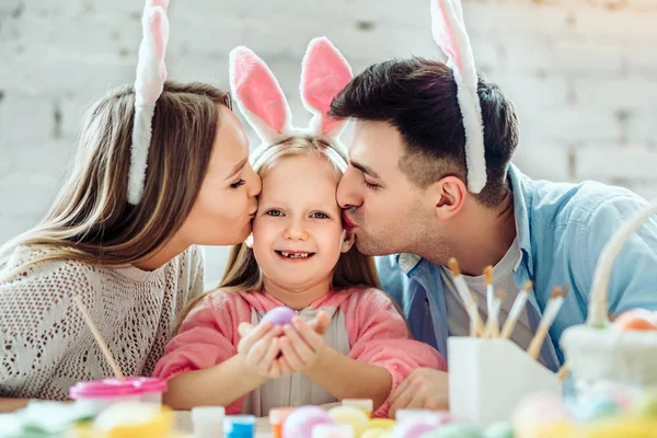 Kocham moich rodziców bardzo za stworzenie atmosfery świąt. Piękny rodzinny farba pisanki razem. Szczęśliwa dziewczynka trzymając w rękach pisanka. — Zdjęcie stockowe