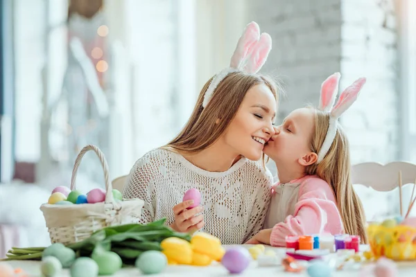 Mama, dziękuję za co wielkanocne przygotowania, tak interesujące i zabawne. Mama i córka są przygotowania do Wielkanocy razem. Na stole jest kosz z jaja wielkanocne, kwiaty i farby. — Zdjęcie stockowe