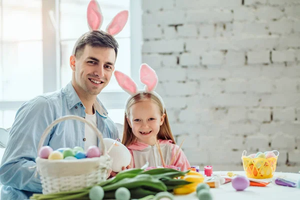 Mein papa ist der beste der welt! vater und tochter bereiten sich auf oster together.on dem tisch ist ein korb mit ostereiern, blumen und farbe. — Stockfoto