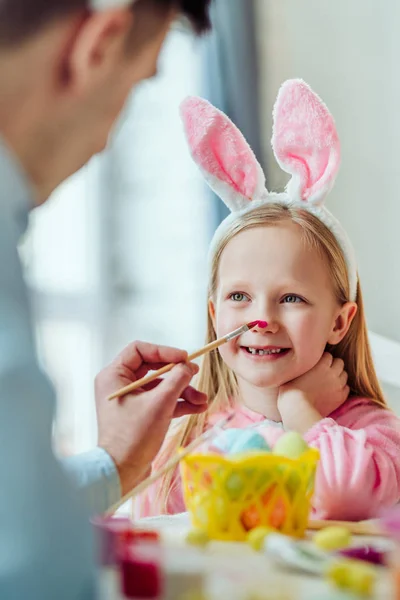 Ich liebe es, mich mit meinem Papa und meiner Tochter auf Ostern vorzubereiten. Papa malt seiner Tochter die Nase. — Stockfoto