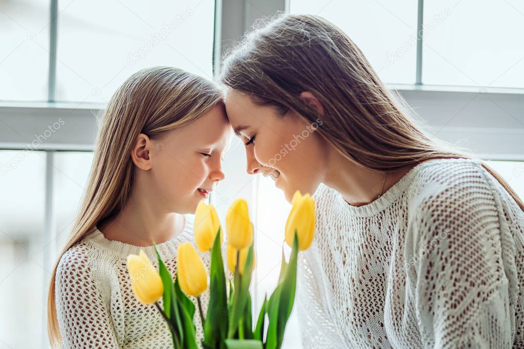 I will always take care of you.Young mother and her daughter putting their heads together while keeping their eyes closed.