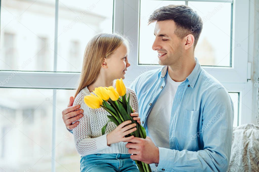 Time with dad is always great.Father gives her daughter a bouquet of tulips.