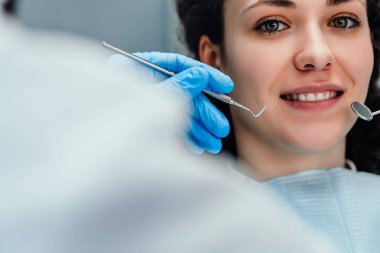 Genç bayan dişçi ofisinde oturuyor ve gülümsüyor. Görüntüyü kapat.