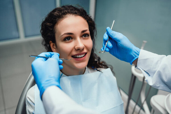 Young beautiful woman with beautiful white teeth sitting on a dental chair. Portrait of a woman with toothy smile sitting during examination at the dental office.
