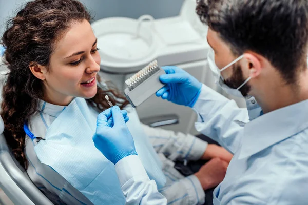 Giovani belle donne in sedia dentista, controllare e selezionare il colore dei denti. Vista da vicino . — Foto Stock