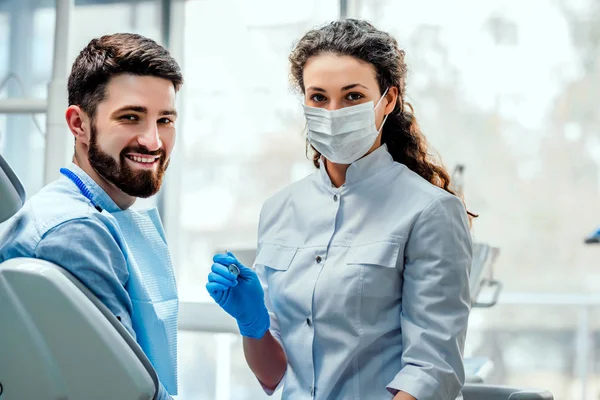 Vue d'un jeune dentiste attrayant expliquant son travail à un patient . — Photo