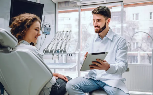 Pessoas, medicina, estomatologia e conceito de cuidados de saúde dentista masculino feliz mostrando computador tablet para paciente mulher no consultório de clínica odontológica . — Fotografia de Stock