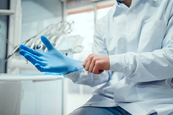 Närbild av manliga läkarens händer sätta på blå steriliserade kirurgiska handskar i den medicinska kliniken. — Stockfoto