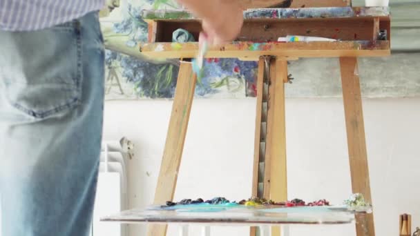 Painter paints picture on blank canvas — Stock Video