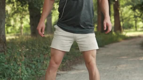 Young man warming up before jogging in park — Stock Video