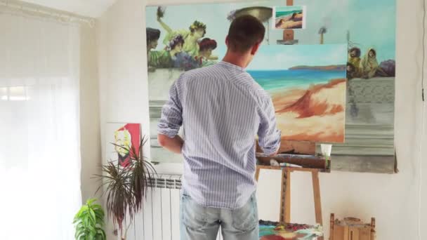 Male painter paints landscape on canvas — Stock Video