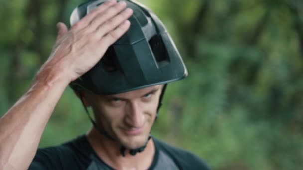 Ciclista hombre golpea su mano en el casco en la cabeza — Vídeo de stock