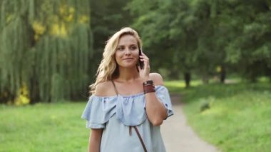 neşeli erkek Park'ta yürüyordunuz telefonda konuşuyor