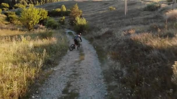 Вид с воздуха на велосипедиста, идущего по горной дороге — стоковое видео