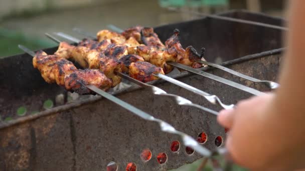 Hands of man turn meat over skewers — Stock Video