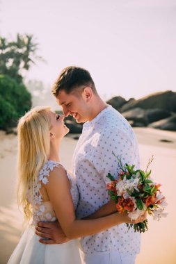 ayakta ve tropik sahilde sarılma yeni evliler