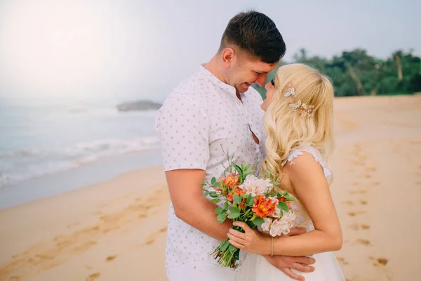 Sposi in piedi e abbracci sulla spiaggia tropicale — Foto Stock
