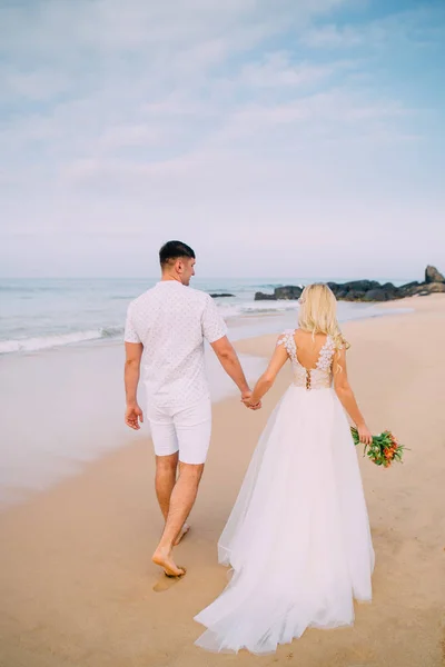Jeunes mariés marchant le long de la plage tropicale, vue arrière — Photo