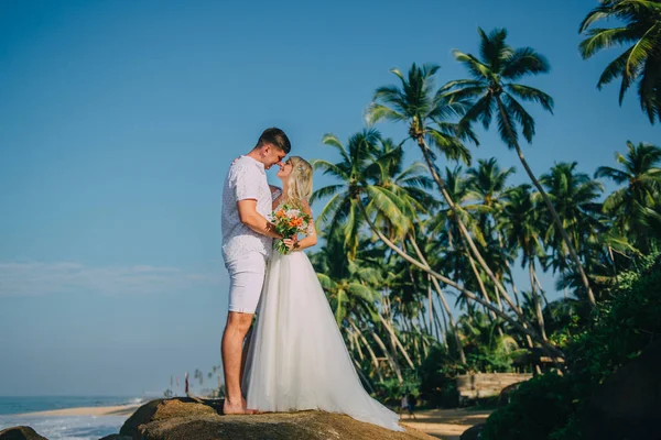 Heureux jeunes mariés câlins sur fond de plage tropicale — Photo