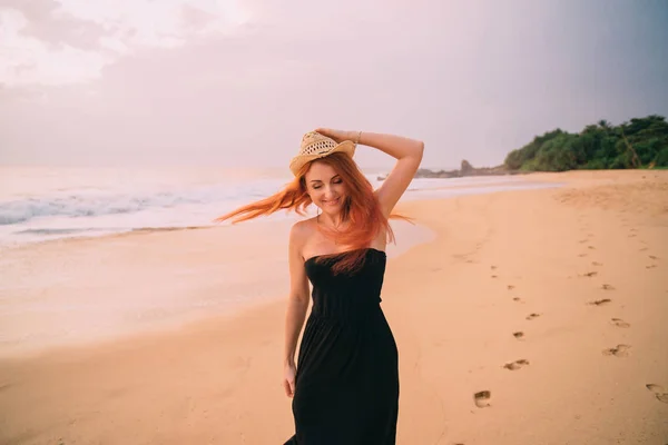 Молода руда жінка, що йде уздовж пляжу на заході сонця — стокове фото